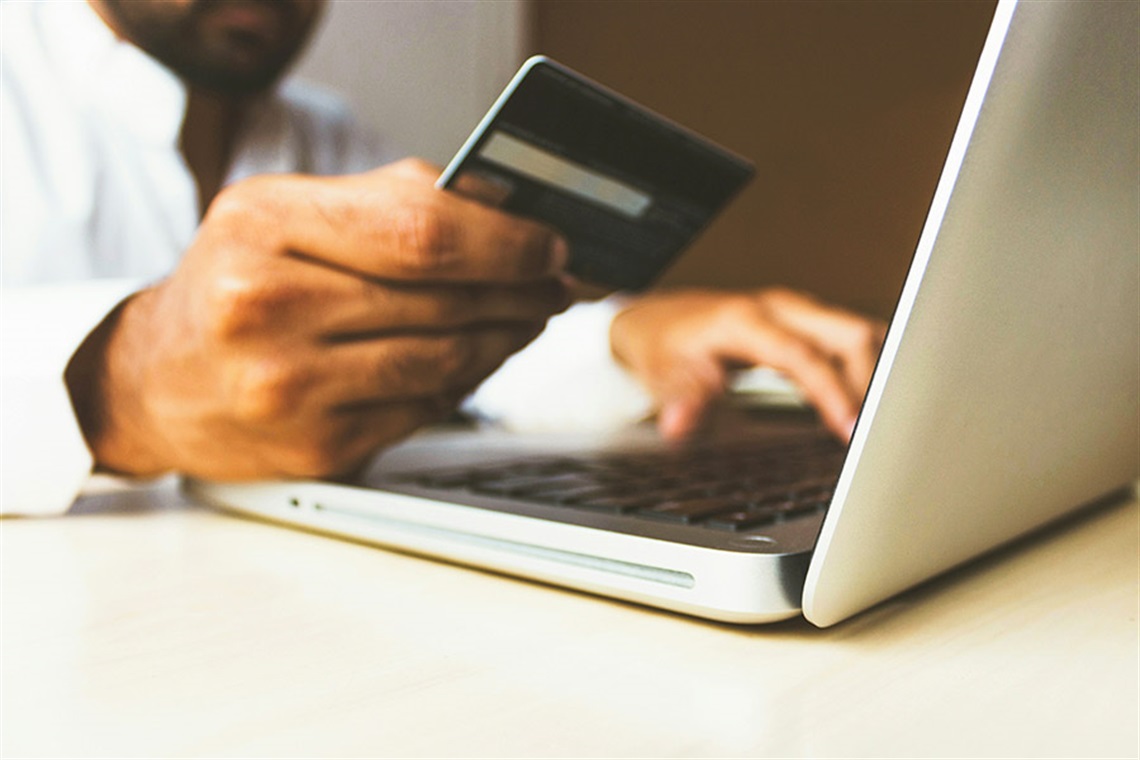 Picture of of someone holding their credit card in front of a laptop. 