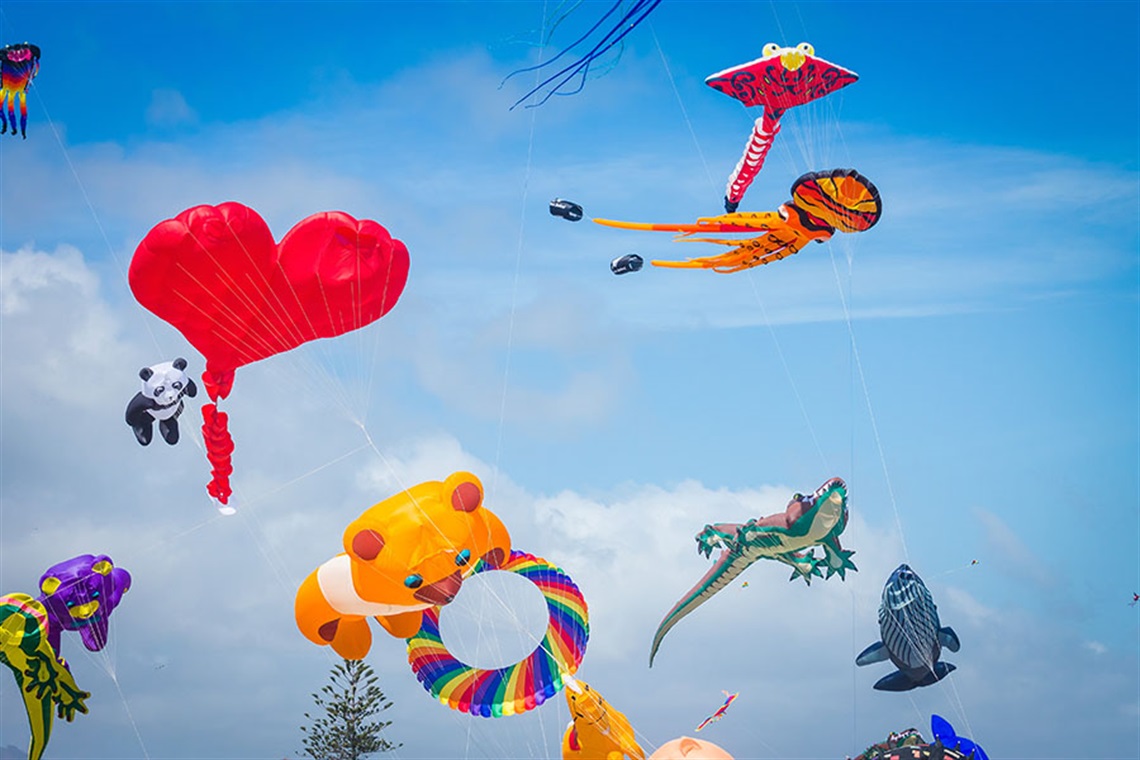 Many colourful kites flying in a blue sky. 