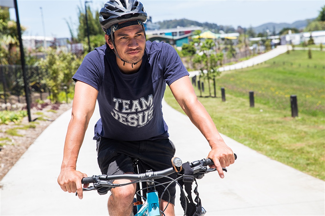 A young man wearing a cycle helmet on the Kamo Shared Path. 