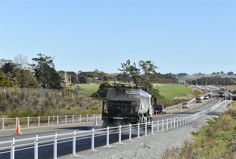 A photo of a truck laying road seal on a stretch of roadworks. 