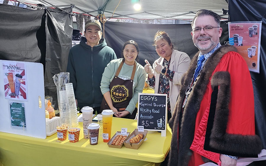 Mayor Vince Cocurullo, dressed in his formal robes, poses with stallholders at Matariki Festival. 