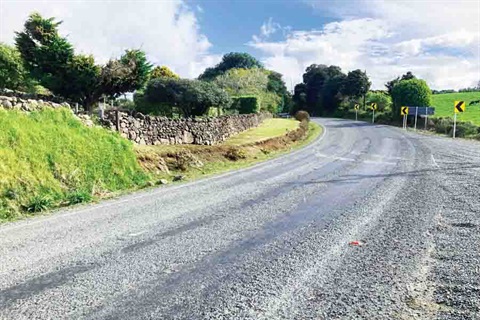 A road with bare patches of stripped seal chips. 