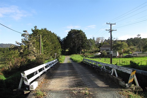 A photo of an old bridge with power lines running along the sides. 