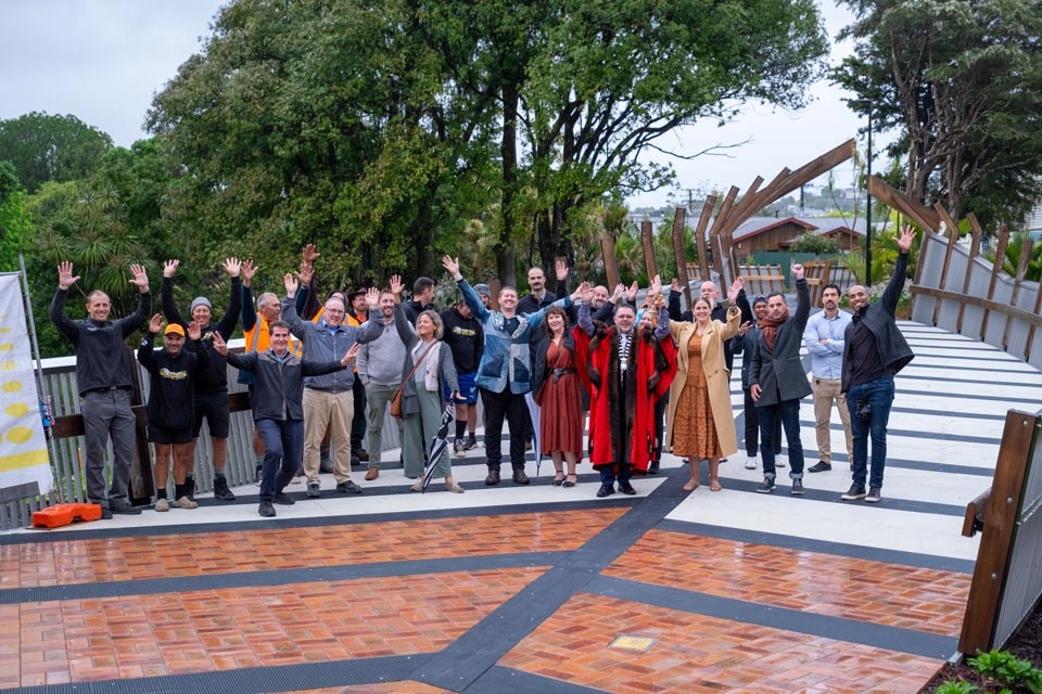 A group of people at Lovers Lane walking and cycling bridge, celebrating the opening with their hands in the air. 