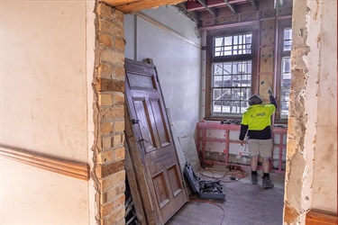 Photo from the Old Municipal Building. A door is leaning against the wall, seen through an empty doorframe.