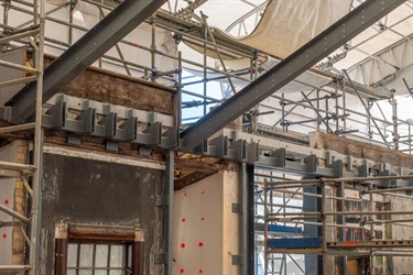 Close-up of restoration work. Metal bars are attached to the wall underneath a temporary walkway.