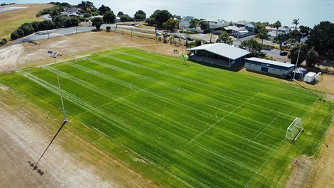 An aerial view of the completed Onerahi Sports Field with the ocean in the background. 