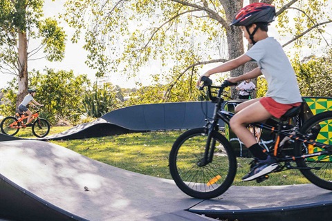 A boy riding his bike on the pump track. 