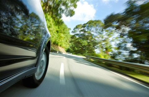 An image of a speeding car on a road. 