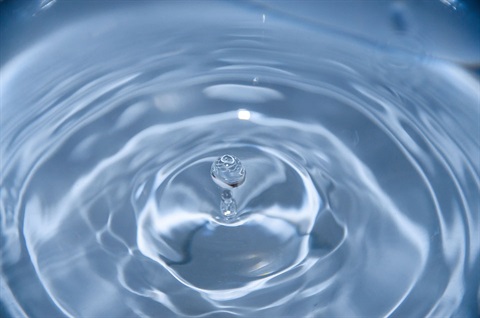 Image of water droplet in a puddle of water. 