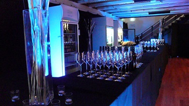 Exhibition Hall bar layout, dark setting with glasses placed evenly on the counter.