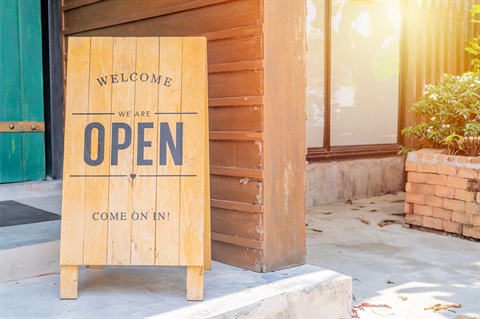 A welcome sign saying we are open, come on in, in front of a business. 