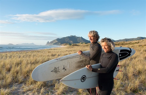 Photo of a man and woman with surfboards at Ocean Beach. 