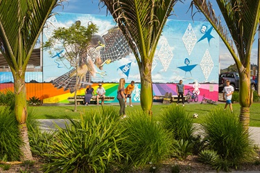 Kids playing in Pocket Park. Artwork of an eagle and a vibrant rainbow are displayed on the wall behind them.