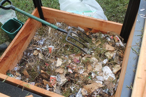 A picture of compost bin with food scraps and leaves for composting. 